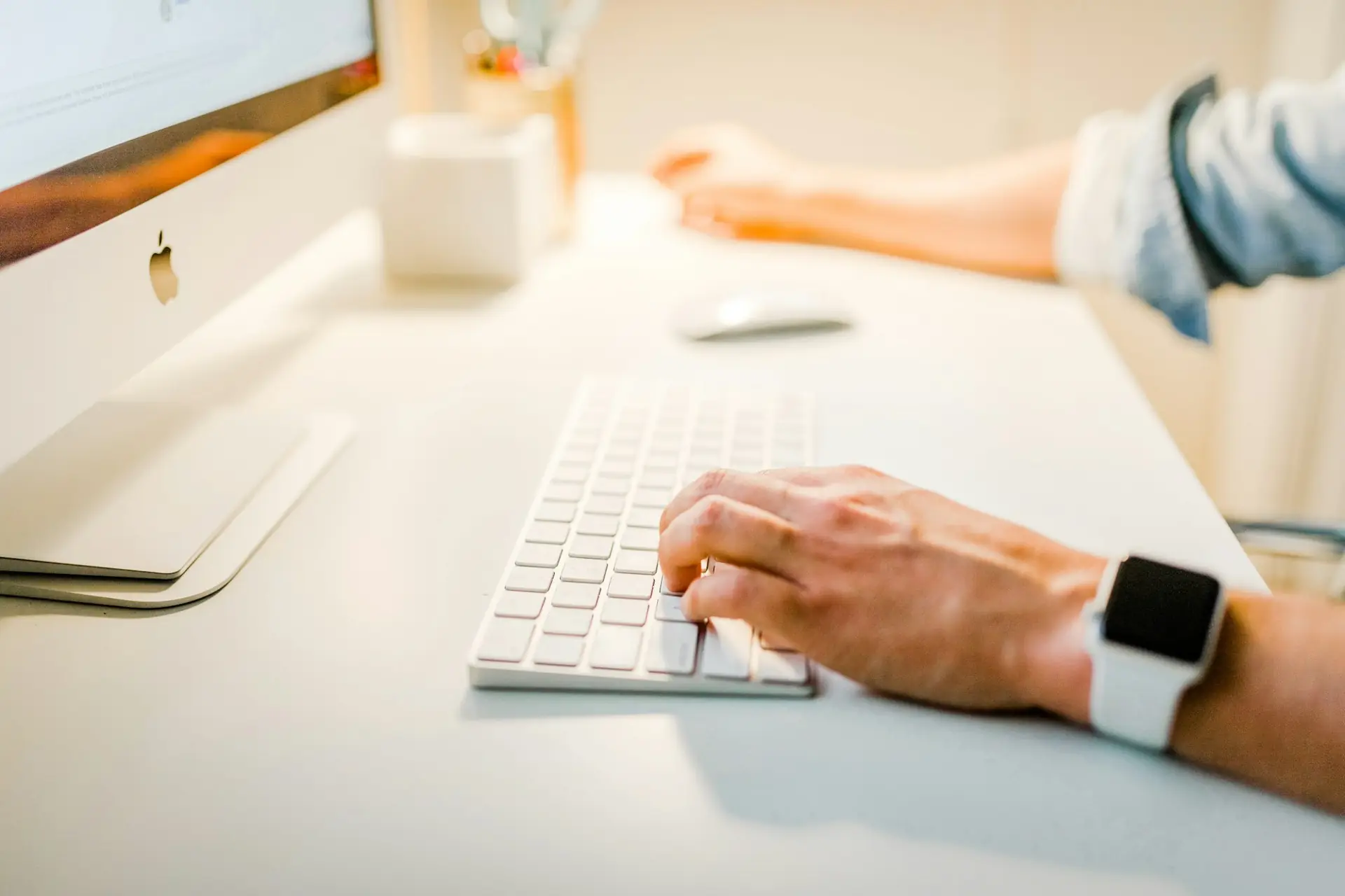 Mains sur le clavier d'un ordinateur de bureau, montre connectée au poignet