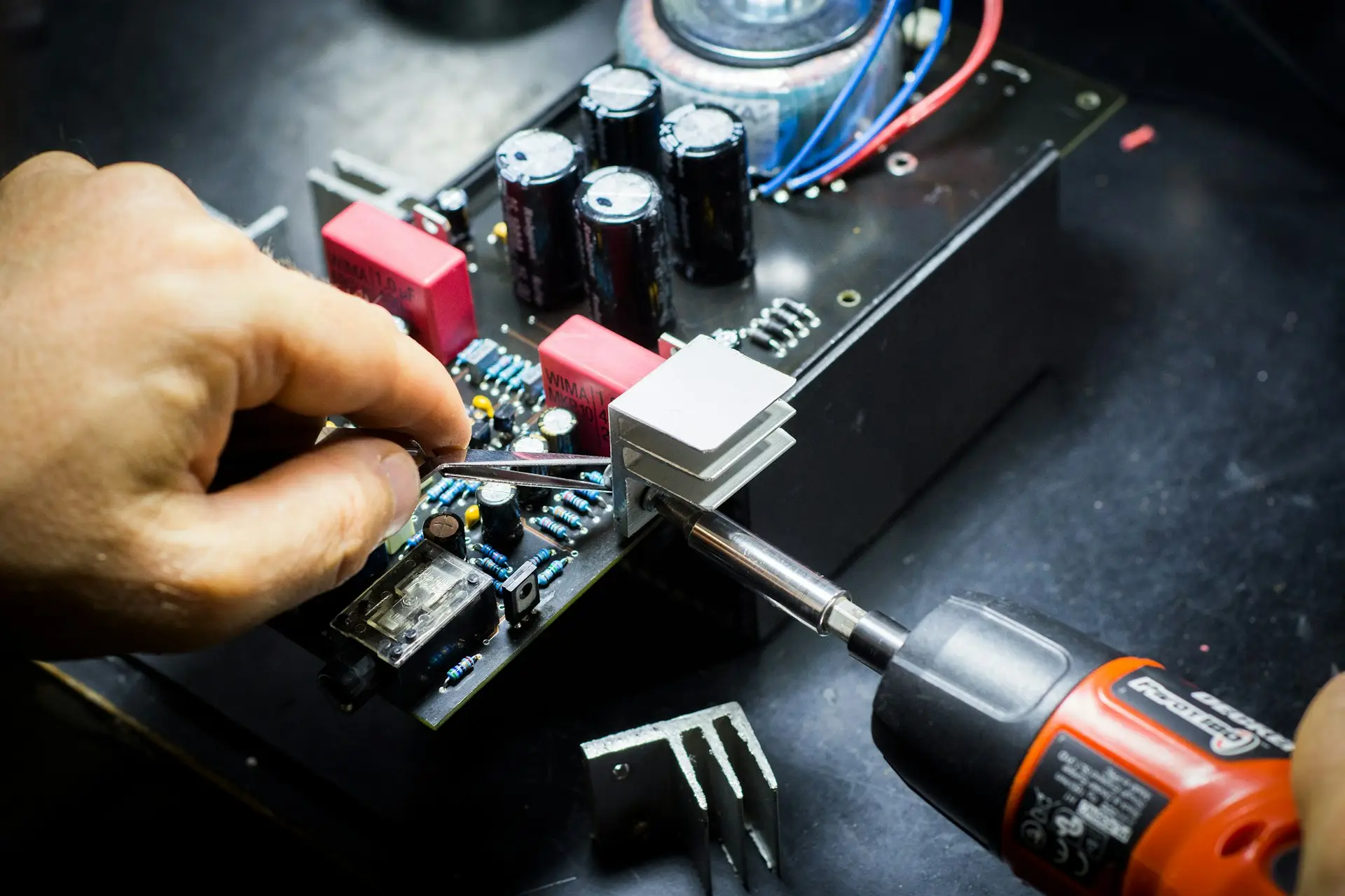 Technicien réparant une carte électronique avec une pince et un tournevis
